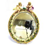 A 19TH CENTURY CONTINENTAL PORCELAIN FRAMED OVAL MIRROR floral encrusted border with pair of cherubs