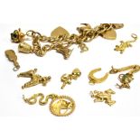 A 9 CARAT GOLD CHARM BRACELET with padlock fastener and safety chain, containing seven assorted