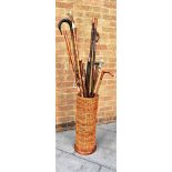 THIRTEEN ASSORTED WALKING STICKS, CANES AND HIKING STICKS in a cylindrical wicker stick stand