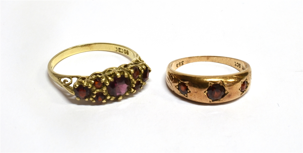 TWO GARNET SET DRESS RINGS comprising a boat shaped head with seven cut garnets, ring size T,