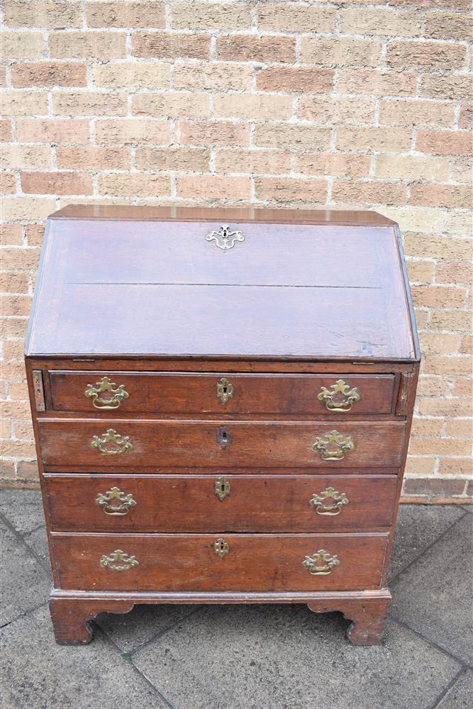 A GEORGE III PROVINICIAL OAK BUREAU with fitted interior above four long graduated drawers, on