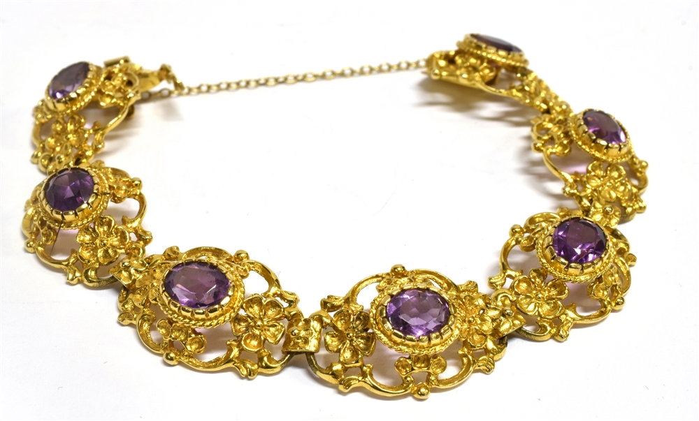 A 9 CARAT GOLD AMETHYST SET BRACELET seven oval openwork links with scroll and flower head