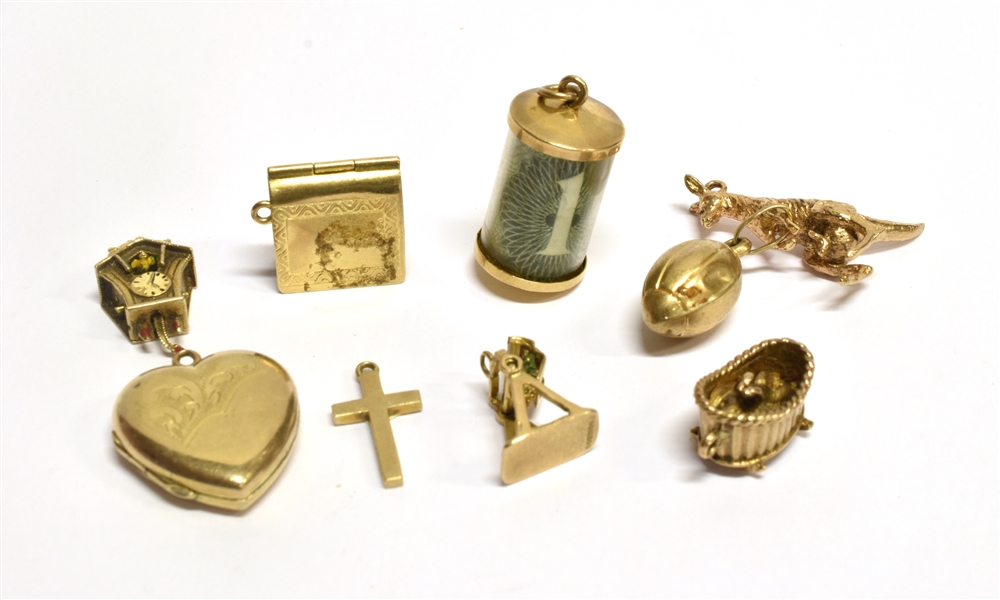 NINE ASSORTED 9 CARAT GOLD CHARMS to include a one pound note in cylinder, kangaroo, cuckoo clock
