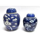 TWO CHINESE GINGER JARS AND LIDS both decorated with prunus blossom on a cracked ice ground, 20.
