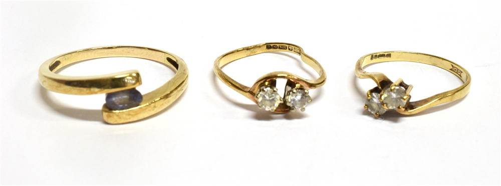 THREE YELLOW GOLD STONE SET CROSSOVER RINGS comprising a blue stone set ring, unmarked, assessed