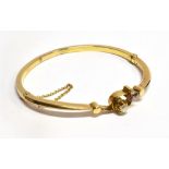 AN EDWARDIAN 15 CARAT GOLD HINGED BANGLE round old cut diamond set to front crossover section,