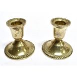 A PAIR OF SILVER DWARF CANDLESTICKS the sconce to round pedestal base, the bases stamped sterling (