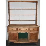 A PINE DRESSER the rack with three shelves, the base fitted with three drawers over pot shelf