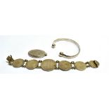 THREE ITEMS OF SILVER JEWELLERY comprising a torque bangle, a coin set bracelet, and an oval locket,