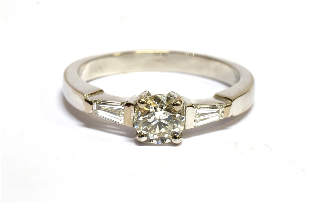 A DIAMOND SOLITAIRE WHITE GOLD RING with diamond set shoulder, the round brilliant cut diamond