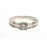 A DIAMOND SOLITAIRE WHITE GOLD RING with diamond set shoulder, the round brilliant cut diamond