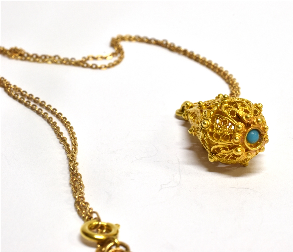 A MIDDLE EASTERN STYLE FILIGREE DROP PENDANT set with a small turquoise on a matched 9 carat gold