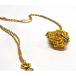 A MIDDLE EASTERN STYLE FILIGREE DROP PENDANT set with a small turquoise on a matched 9 carat gold