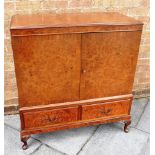 A WALNUT COCKTAIL CABINET with pair of doors opening to shelved interior above pair of drawers, on