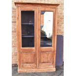 A LARGE PITCH PINE BOOKCASE the part glazed doors opening to four adjsutable shelves, 118cm wide