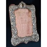 A SILVER PHOTO FRAME the rectangular frame with silver, front of embossed shell, scroll and cherub