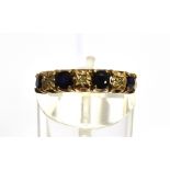 A 9CT GOLD SEVEN STONE HALF HOOP RING four round cut blue sapphires alternating with three small