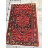 A RED GROUND RUG with central medallion and stylised birds and animals, 134cm x 206cm