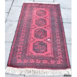 TWO RED GROUND RUGS: one with four central guls 105cm x 193cm; another with three guls 86cm x 123cm