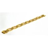 A 14CT GOLD BRACELET the barrel shaped openwork links with textured finished borders and integral