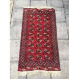 A RED GROUND BOKHARA RUG the central filed with three rows of guls, 113cm x 208cm