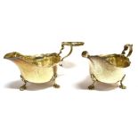 A PAIR OF SILVER SAUCEBOATS of traditional form with scroll handles and waved borders on three paw