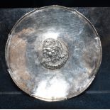 AN OMAR RAMSDEN SMALL DISH of hammered finish, the applied two headed central boss with scroll