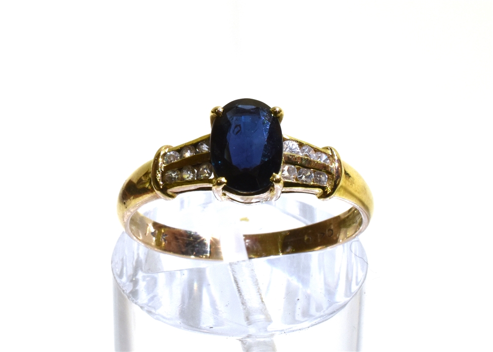 A 14CT GOLD SAPPHIRE SINGLE STONE RING WITH WHITE STONE SET SHOULDERS the oval cut blue sapphire