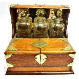 AN EDWARDIAN EPNS MOUNTED OAK FRAMED TANTALUS with three associated decanters and stoppers with