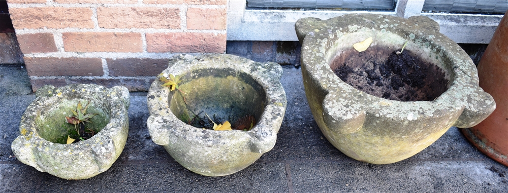 A GRADUATED SET OF THREE STONE MORTARS the largest 54cm wide 26cm high