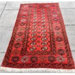 A RED GROUND RUG the central field with two rows of guls, 100cm x 180cm; and another similar smaller