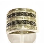 A BLACK AND WHITE DIAMOND SET SILVER BAND RING the front section comprising five rows of alternating