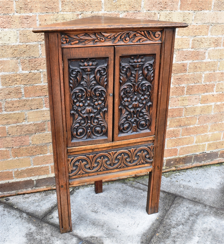 A CARVED OAK CORNER CUPBOARD the doors opening to shaped shelf within, 69cm wide 111cm high