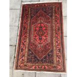 A RED GROUND RUG with central medallion, 133cm x 209cm