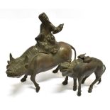A BRONZE GROUP MODELLED AS A FIGURE SEATED ON A WATER BUFFALO 27.5cm high; together with another