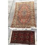 A RED GROUND RUG with allover foliate design (faded) 217cm x 130cm; and another small rug, 110cm x