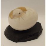 A Chinese carved ivory chick in egg on wooden stand Condition Report: Available upon request