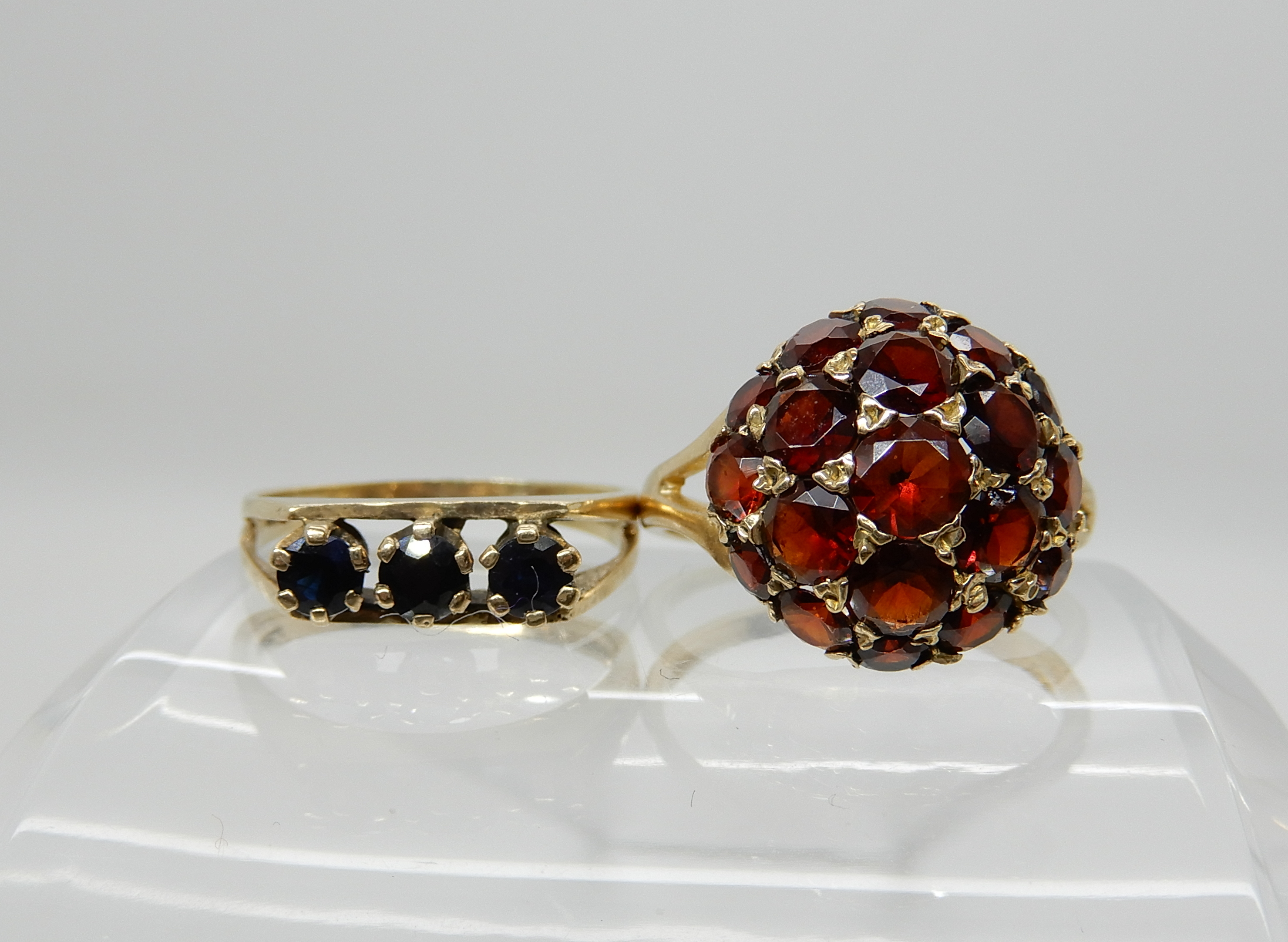 A 9ct gold garnet set dome ring, size O1/2, together with a retro sapphire set ring size L1/2,