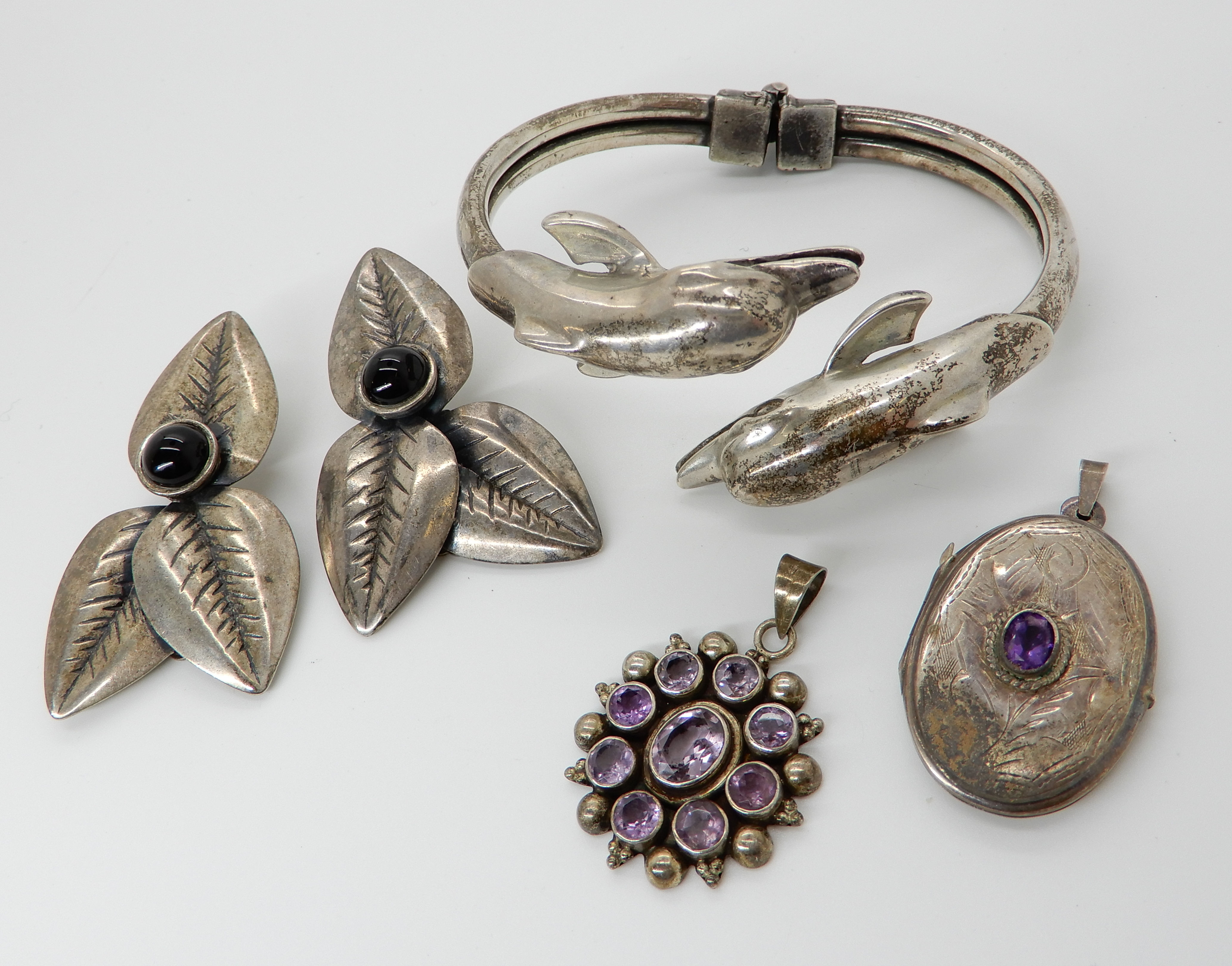 A silver dolphin bangle, two amethyst pendants and a pair of earrings Condition Report: Not