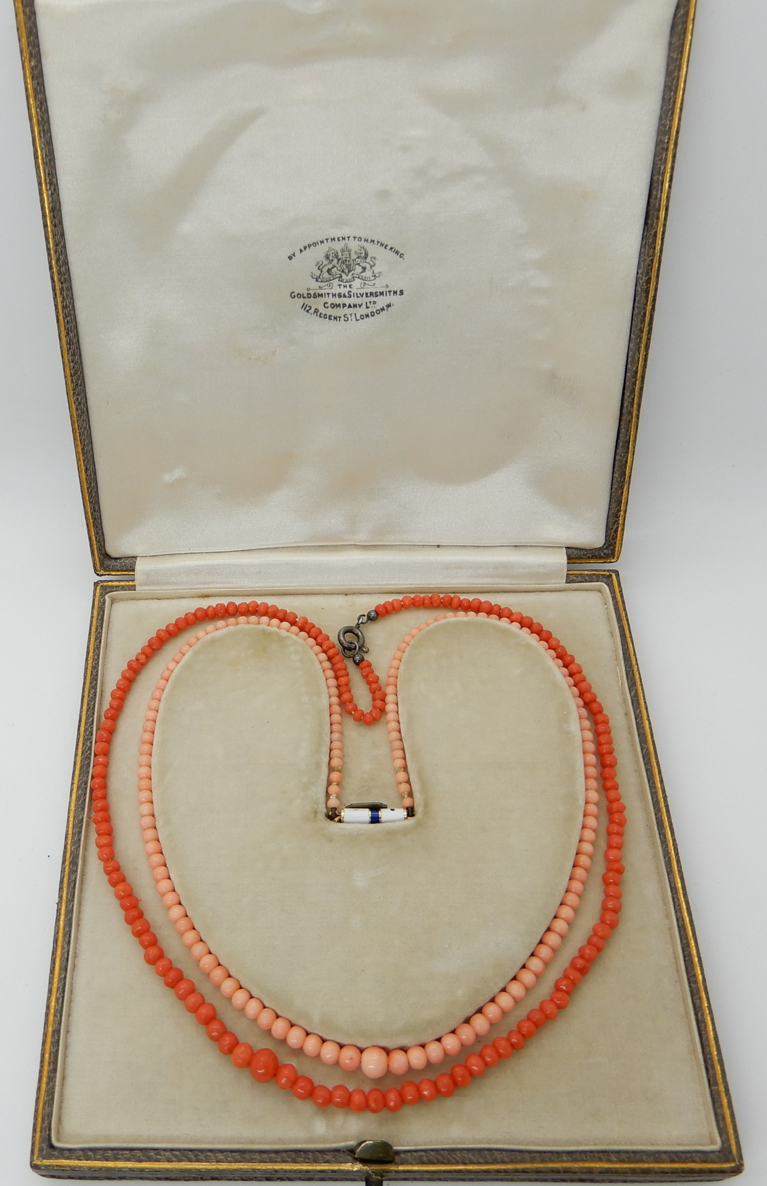 A string of coral beads with an enamelled yellow metal clasp, length 36cm, together with a further