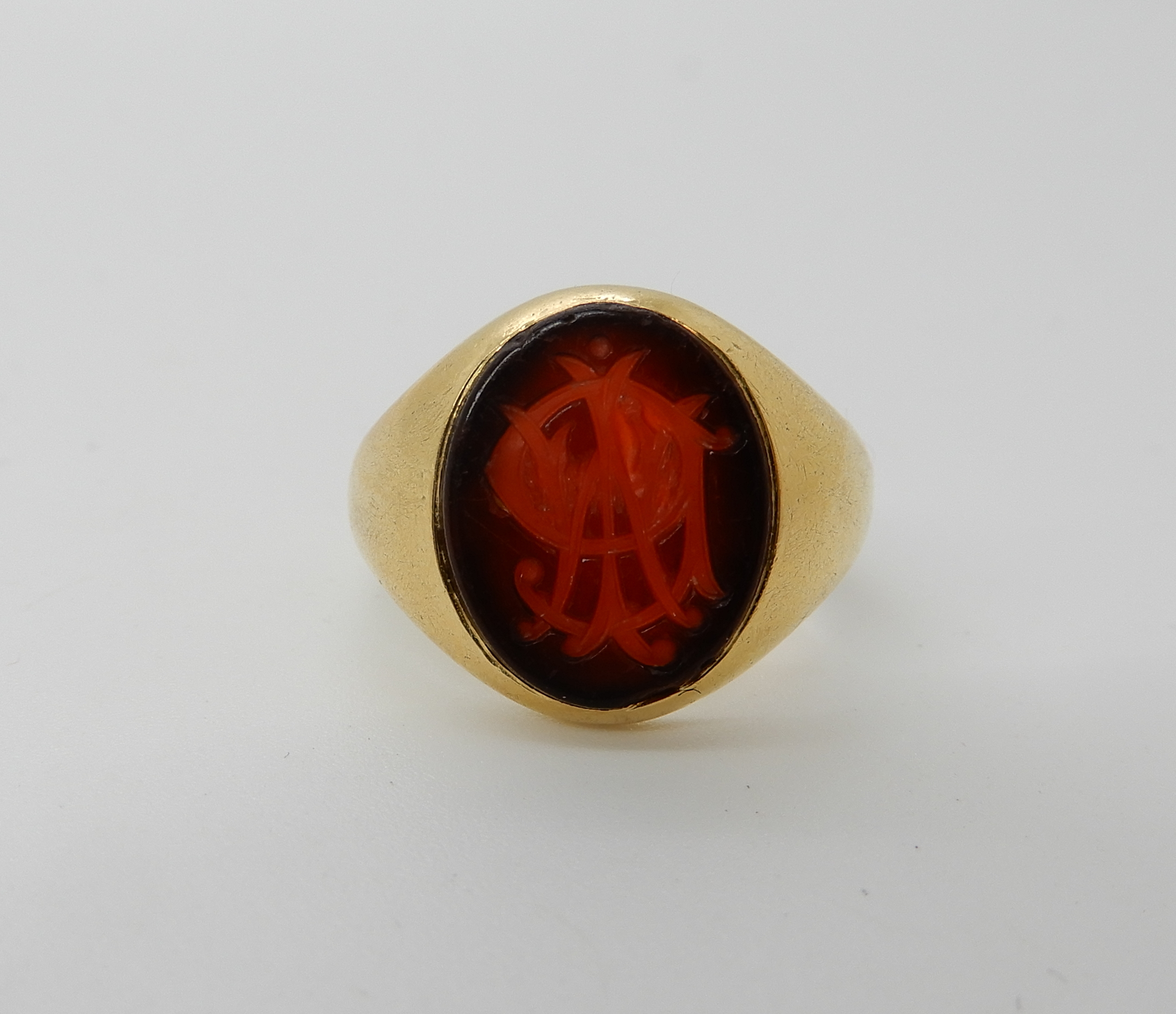 A bright yellow metal signet ring set with a intaglio monogrammed agate, size K, weight 6.2gms