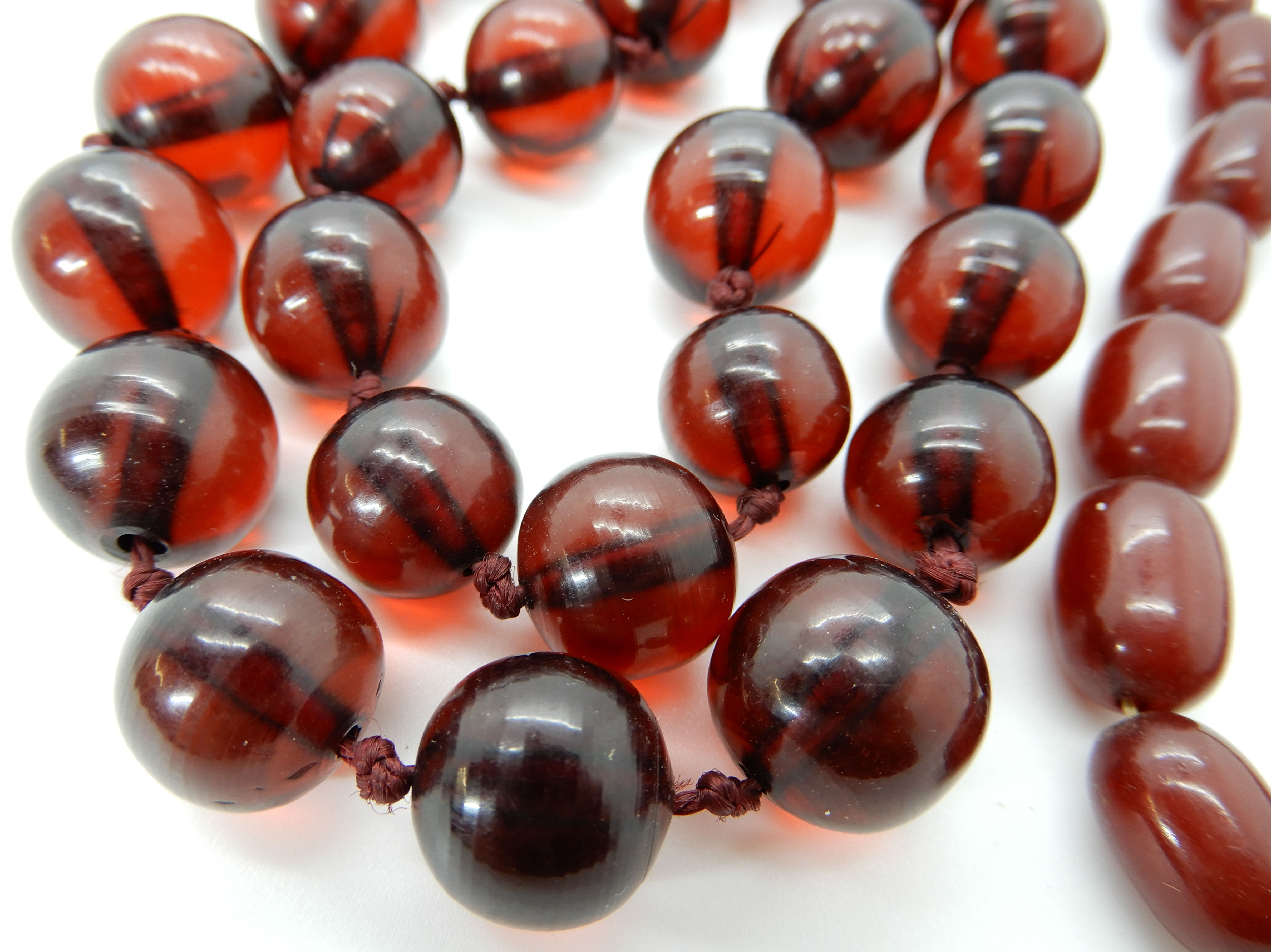 Two strings of cherry amber coloured beads, round beads weight 106.2gms, oval beads weight 25.5gms - Image 2 of 3
