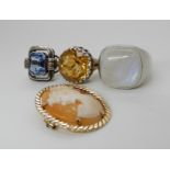 A 9ct gold mounted shell cameo brooch, and three silver or white metal gem set rings to include