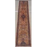 A PINK GROUND SAROUGH RUNNER with blue central medallion and border, 380cm x 85cm Condition