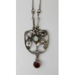 AN ART NOUVEAU WHITE METAL OPAL AND GARNET SET PENDANT the opal nestling among leaves and berries.