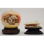 A CHINESE CARVED APPLE stained and detailed with figures on a bridge, beneath pine trees, 5cm high