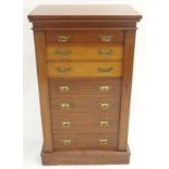 AN OAK WELLINGTON SECRETAIRE CHEST the second and third drawer fitted as a secretaire on a plinth