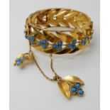 A BRIGHT YELLOW METAL LEAF PATTERN BANGLE set with turquoise glass cabouchons, simple pin clasp with