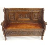 AN OAK HALL BENCH with three carved back panels, lidded seat and bearded lion arms and a floral