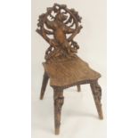 A BLACK FOREST CARVED HALL CHAIR the back carved with a bear standing within a tree branch arbour,